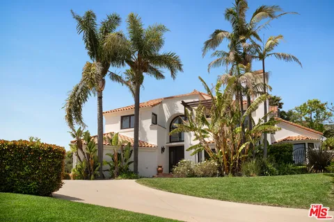 a view of a white house with a big yard and palm trees
