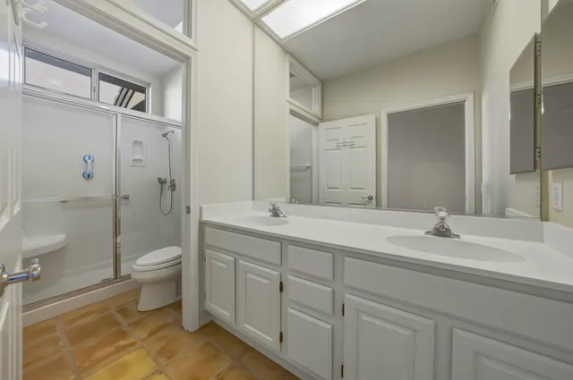 a spacious bathroom with a double vanity sink toilet and a shower