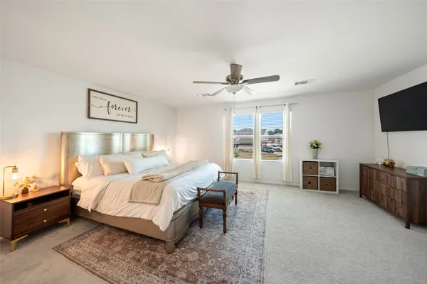 a spacious bedroom with a bed and a flat screen television