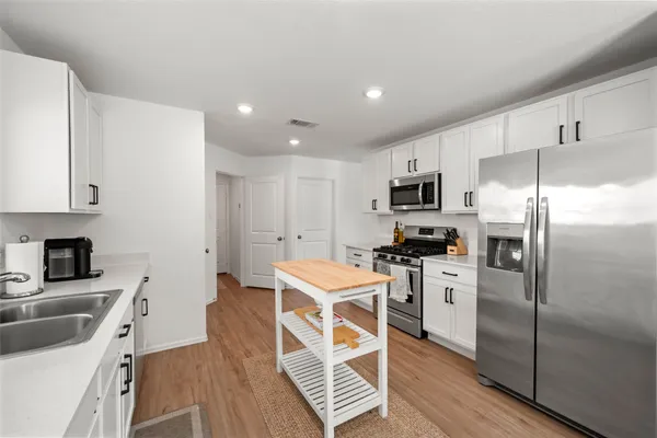 a kitchen with granite countertop a refrigerator stove top oven and sink