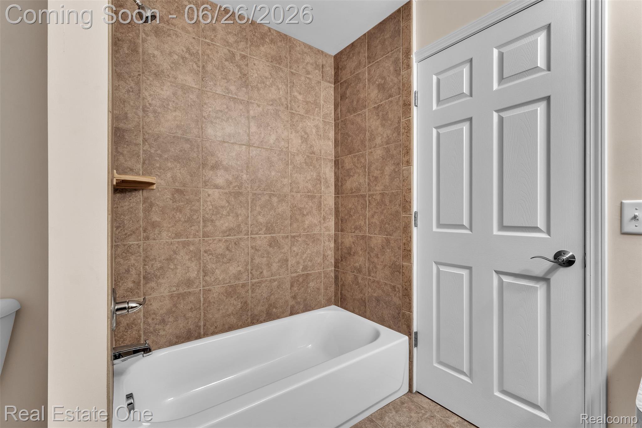 41590 Mitchell Road Novi, MI 48377 - Photo 28 of 45 Bathtub with tiled surround, brushed nickel fixtures, and a corner shelf