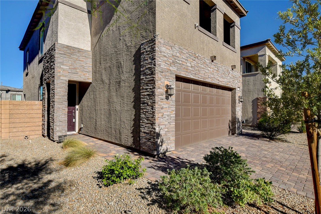 9688 Rankin Rdg Court Las Vegas, NV 89178 - Photo 4 of 53 A striking exterior features a textured facade with stacked stone accents and a paver driveway.