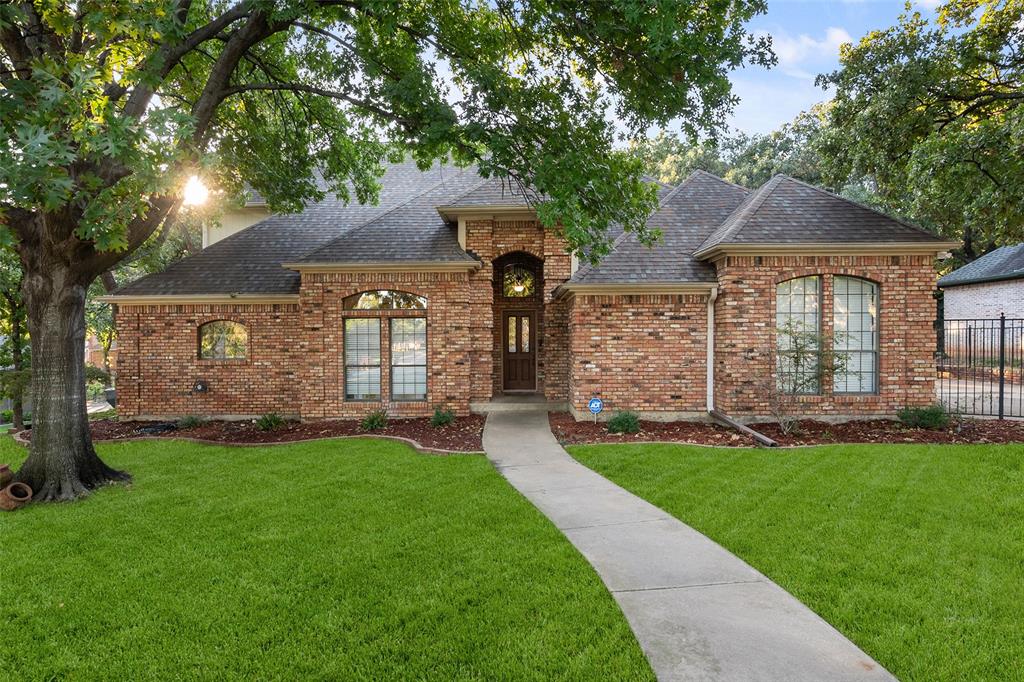 French country inspired facade featuring roof with shingles and brick siding