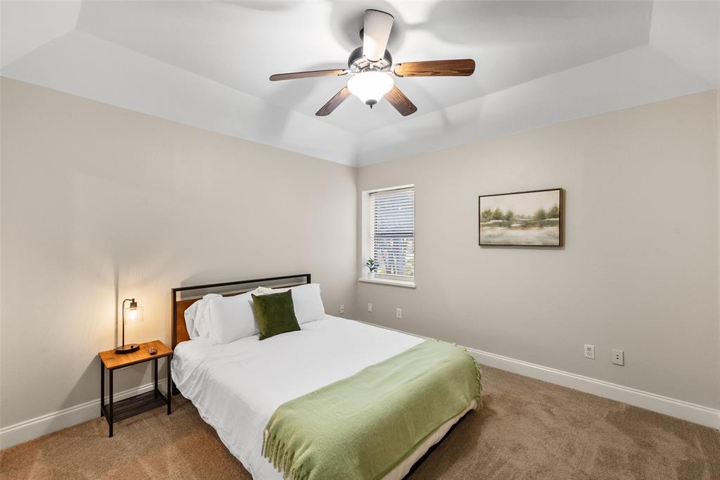 424 Windjammer Lane Azle, TX 76020 - Photo 19 of 37 Carpeted bedroom featuring a tray ceiling and a ceiling fan