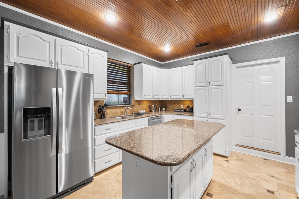 424 Windjammer Lane Azle, TX 76020 - Photo 8 of 37 Kitchen featuring appliances with stainless steel finishes, a textured wall, white cabinetry, light stone countertops, and light tile patterned floors