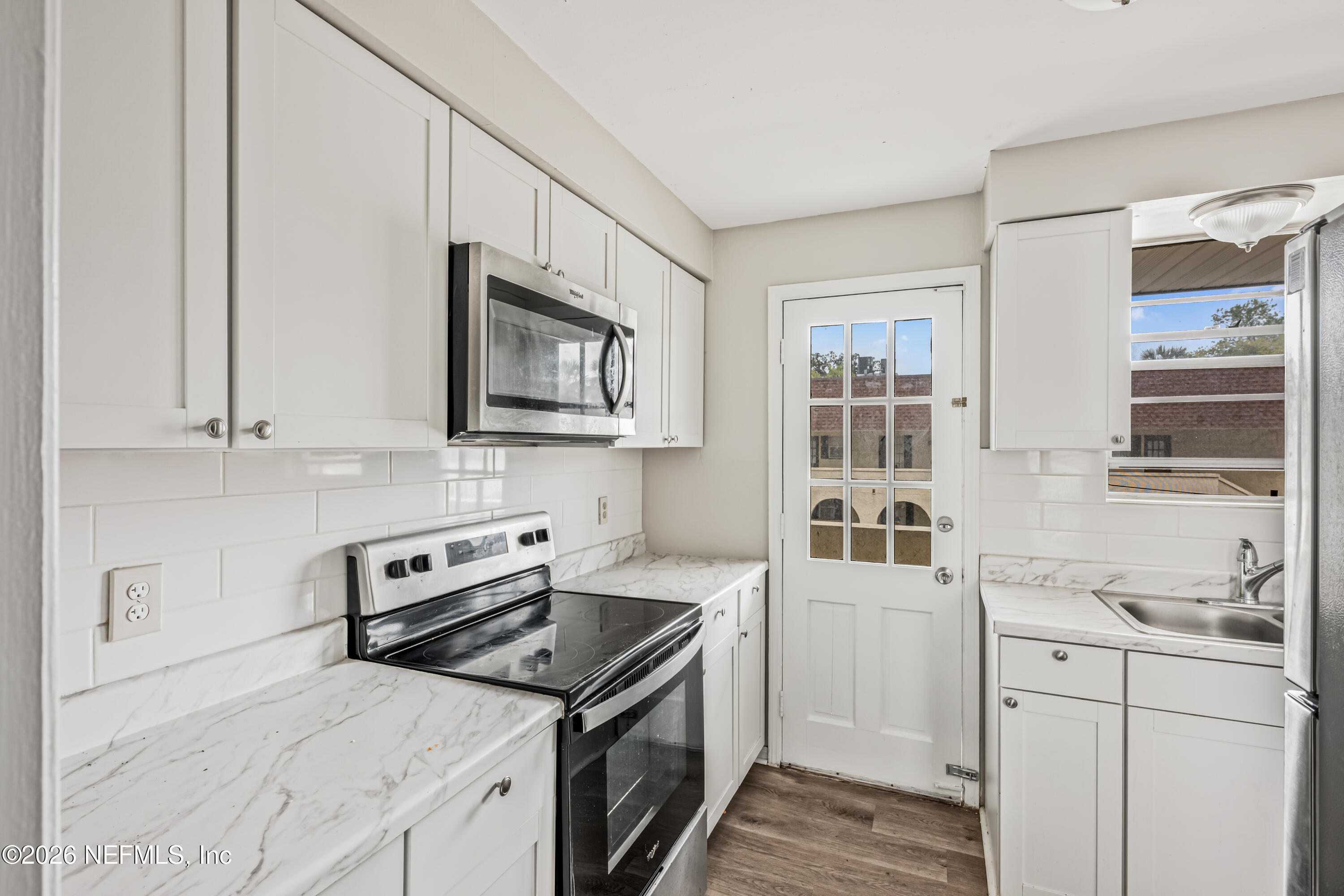 1716 El Camino Road, Unit 6 Jacksonville, FL 32216 - Photo 8 of 18 a kitchen with stainless steel appliances white cabinets and a stove top oven
