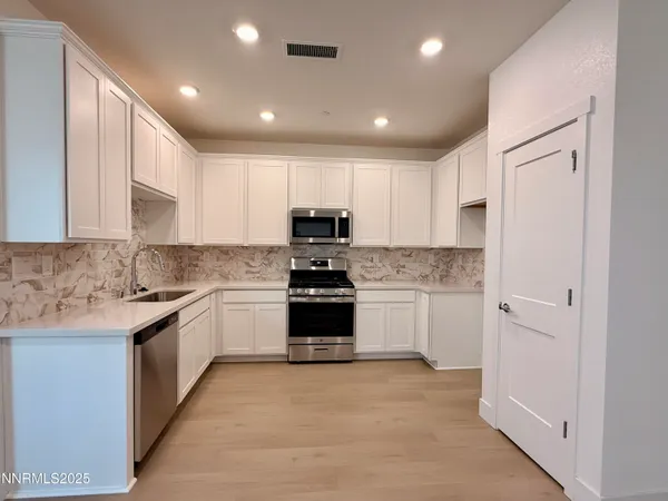 a kitchen with granite countertop white cabinets and stainless steel appliances