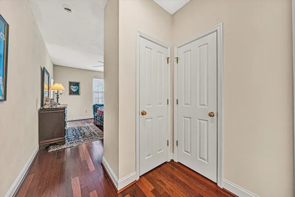 a view of a hallway with wooden floor and a bathroom