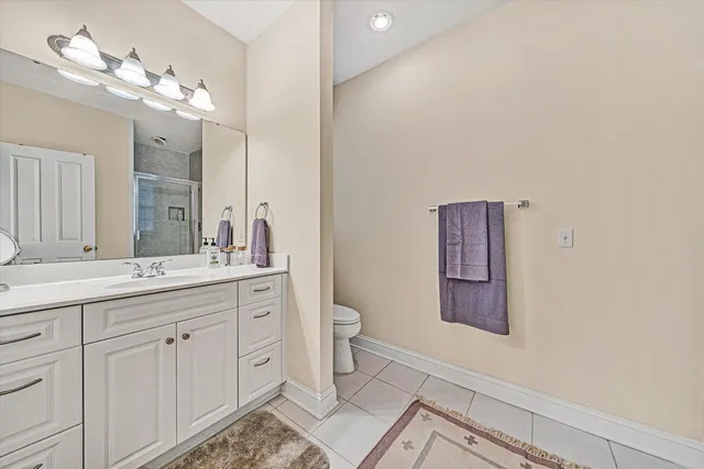a spacious bathroom with a double vanity sink a toilet and a mirror