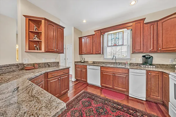 a kitchen with stainless steel appliances granite countertop a stove a sink dishwasher and cabinets with wooden floor