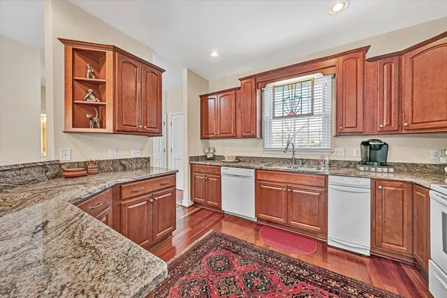 a kitchen with stainless steel appliances granite countertop a stove a sink dishwasher and cabinets with wooden floor