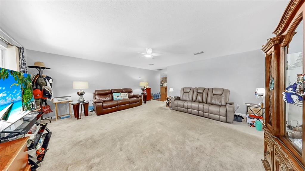 38919 3rd Avenue Zephyrhills, FL 33542 - Photo 4 of 36 a living room with furniture a flat screen tv and a book shelf