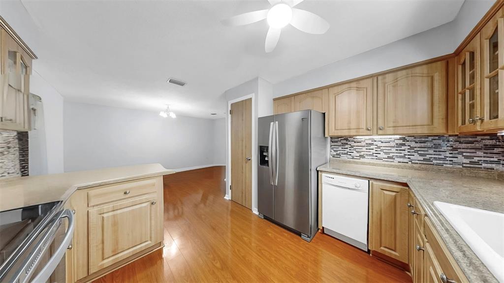 38919 3rd Avenue Zephyrhills, FL 33542 - Photo 8 of 36 a kitchen with stainless steel appliances granite countertop a refrigerator a stove and a sink with wooden floor
