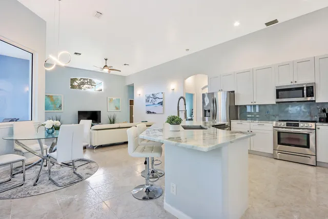 a large white kitchen with a stove a sink a dining table and chairs