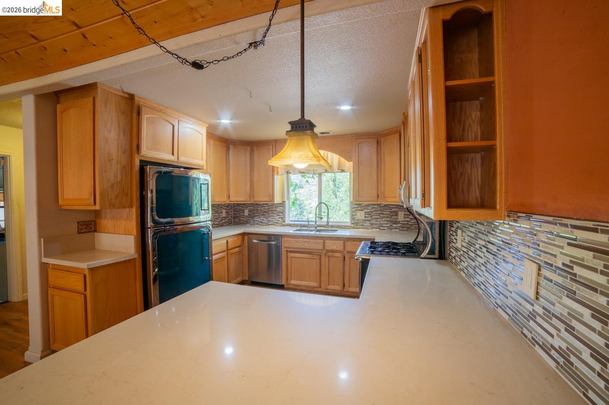 22401 Ridge Road Twain Harte, CA 95383 - Photo 14 of 52 Kitchen featuring wood cabinetry, light-toned countertops, a glass tile backsplash, stainless steel appliances, and recessed lighting