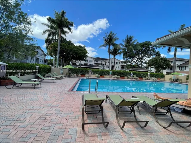 a view of a patio with table and chairs under an umbrella with potted plants