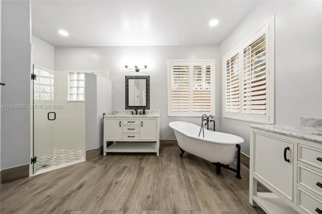 a spacious bathroom with double vanity a window and a bathtub