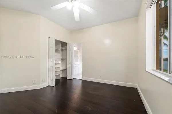 an empty room with wooden floor chandelier fan and windows