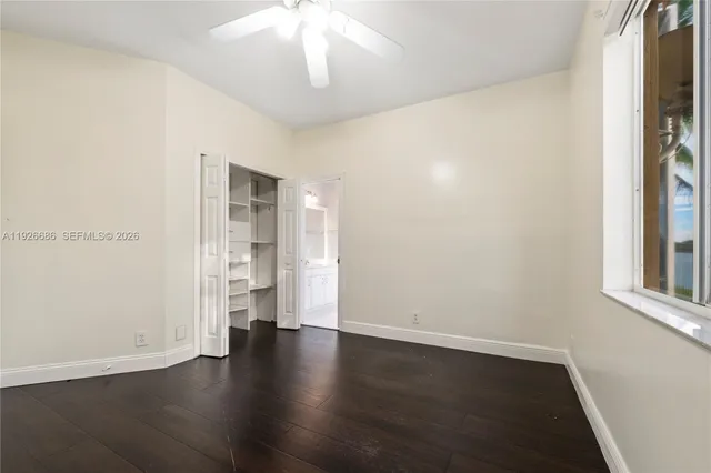 an empty room with wooden floor chandelier fan and windows