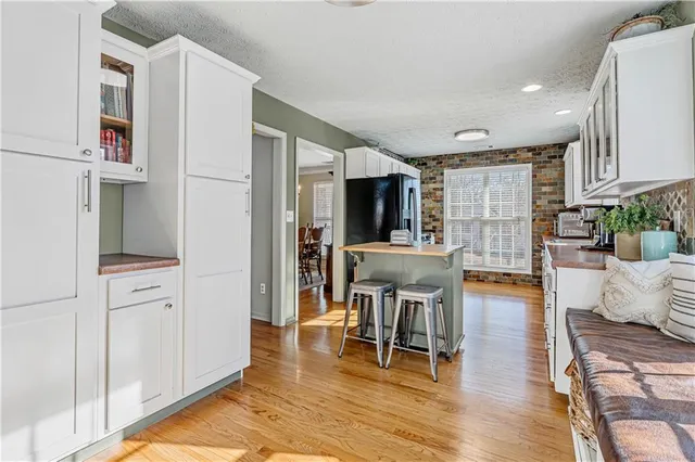 a kitchen with stainless steel appliances a dining table chairs and refrigerator