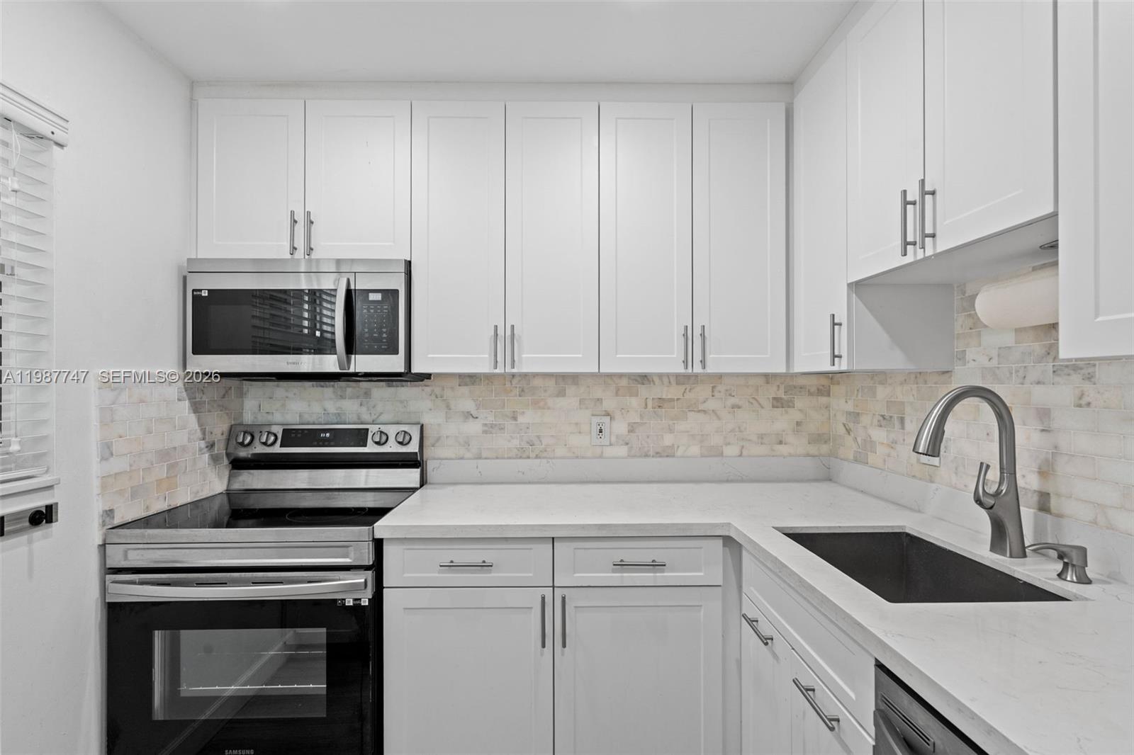 7765 Southwest 86th Street, Unit F2303 Miami, FL 33143 - Photo 14 of 50 a kitchen with stainless steel appliances granite countertop a sink stove and microwave