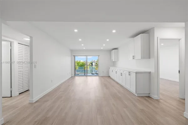 a view of an empty room with wooden floor and windows