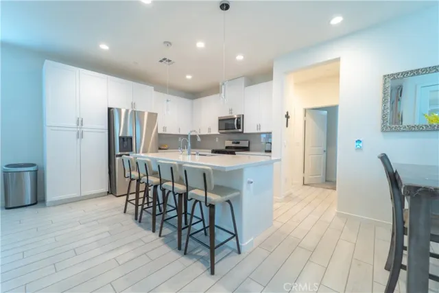 a kitchen with stainless steel appliances a dining table chairs and wooden floors