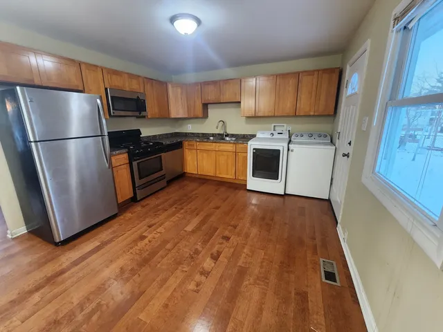 a kitchen with granite countertop a refrigerator a sink dishwasher and a stove top oven