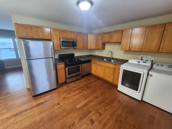 a kitchen with granite countertop wooden floors stainless steel appliances and sink