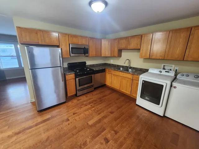 a kitchen with granite countertop wooden floors stainless steel appliances and sink