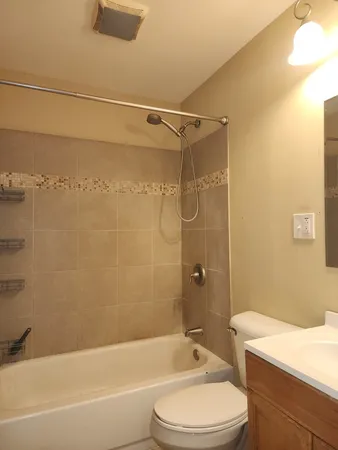 a bathroom with a bathtub shower sink vanity mirror and toilet