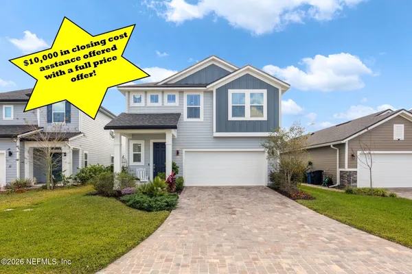 a view of a white house with a big yard and potted plants
