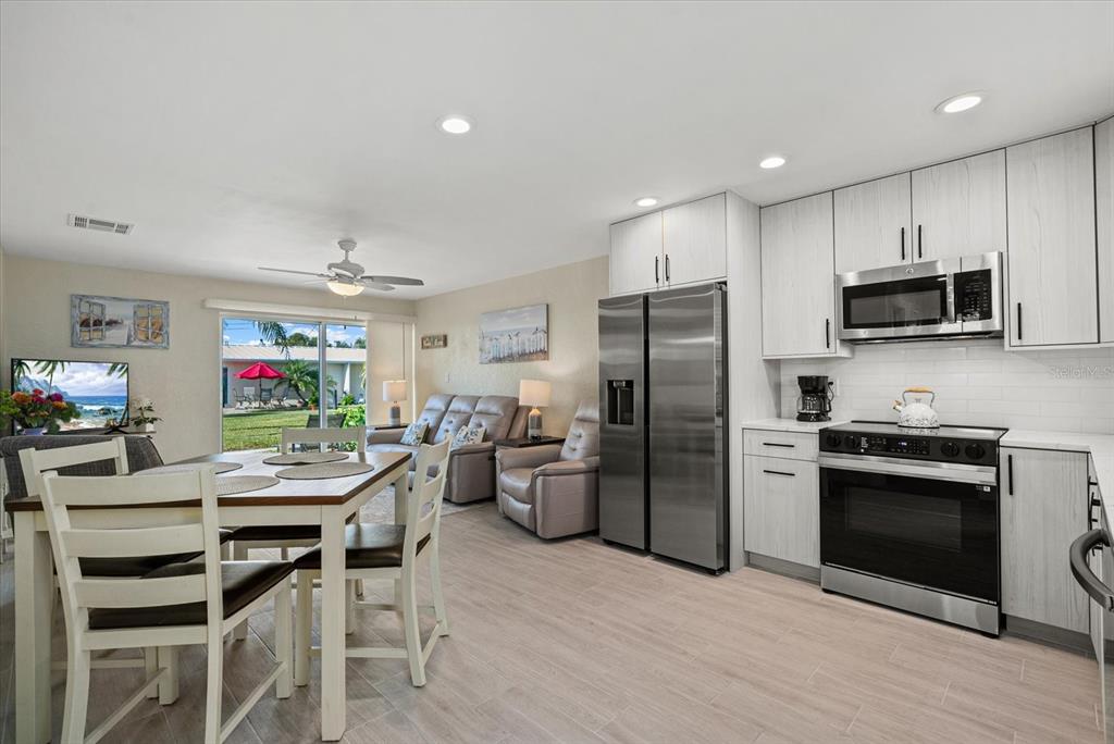5830 Midnight Pass Road, Unit 63 Sarasota, FL 34242 - Photo 2 of 27 a kitchen with stainless steel appliances kitchen island granite countertop a refrigerator stove top oven dining table and chairs