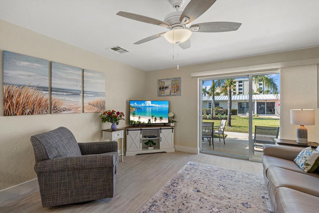 5830 Midnight Pass Road, Unit 63 Sarasota, FL 34242 - Photo 9 of 27 a living room with furniture a flat screen tv and a floor to ceiling window