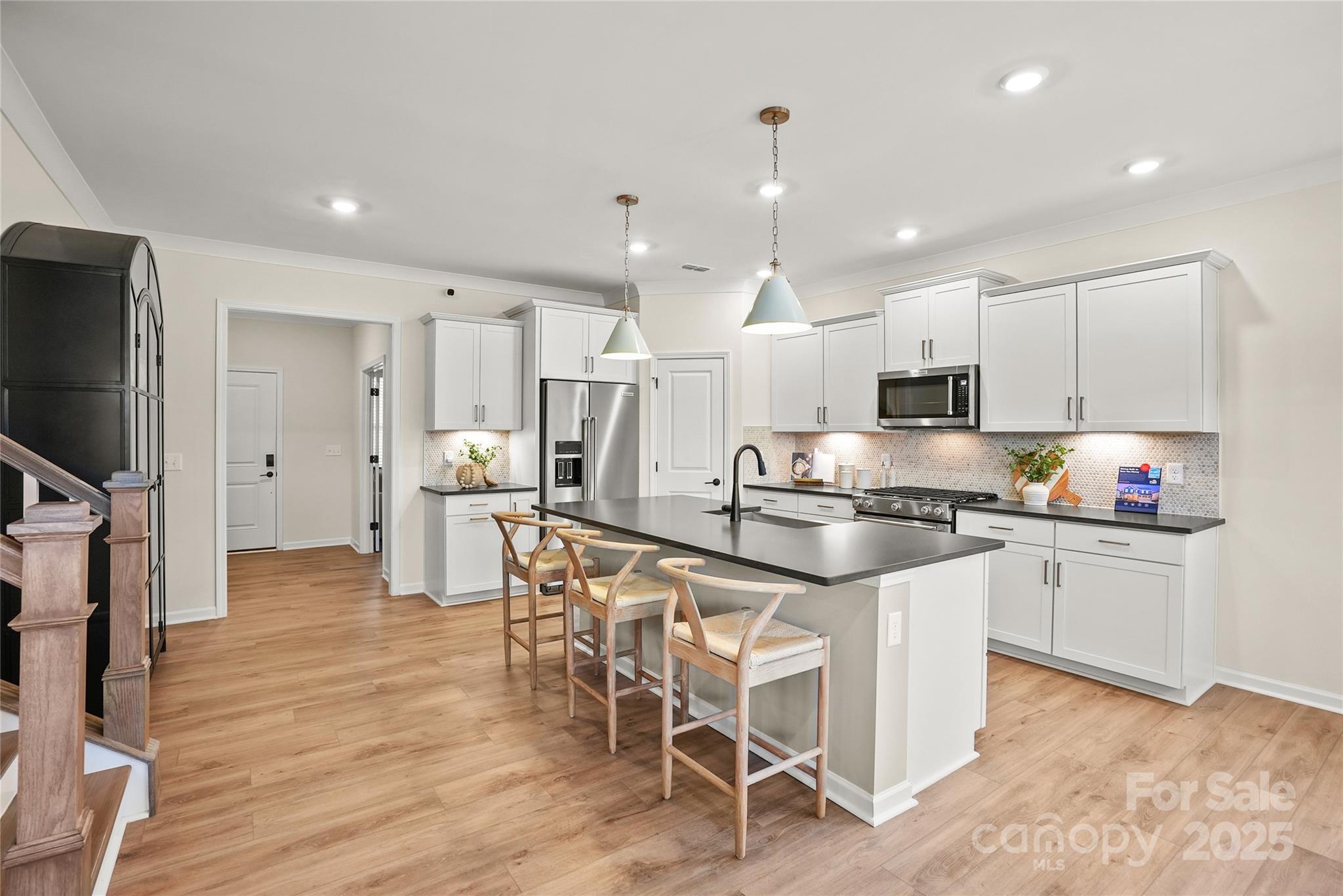 13736 Roderick Drive, Unit 171 Huntersville, NC 28078 - Photo 4 of 14 a kitchen with stainless steel appliances kitchen island granite countertop a refrigerator a stove a sink a dining table and chairs with wooden floor
