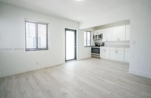 a view of a kitchen with a sink stove cabinets and empty room