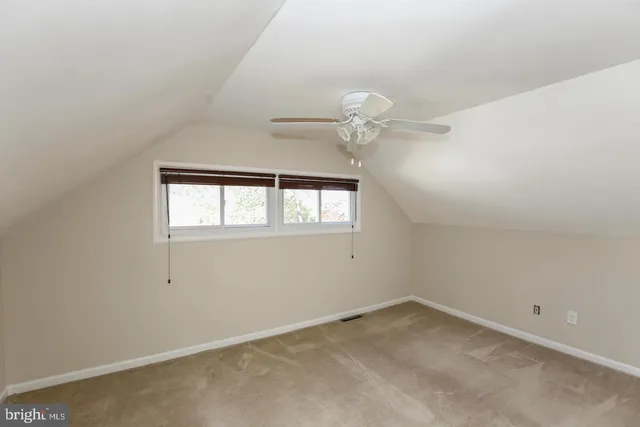 an empty room with a chandelier fan and windows