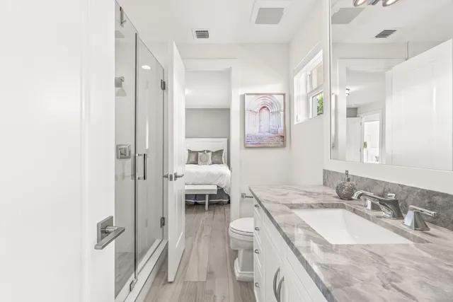a en suite bathroom with a granite countertop double vanity sink a mirror and a shower
