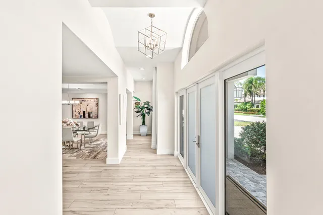 a view of a hallway view with wooden floor and a chandelier