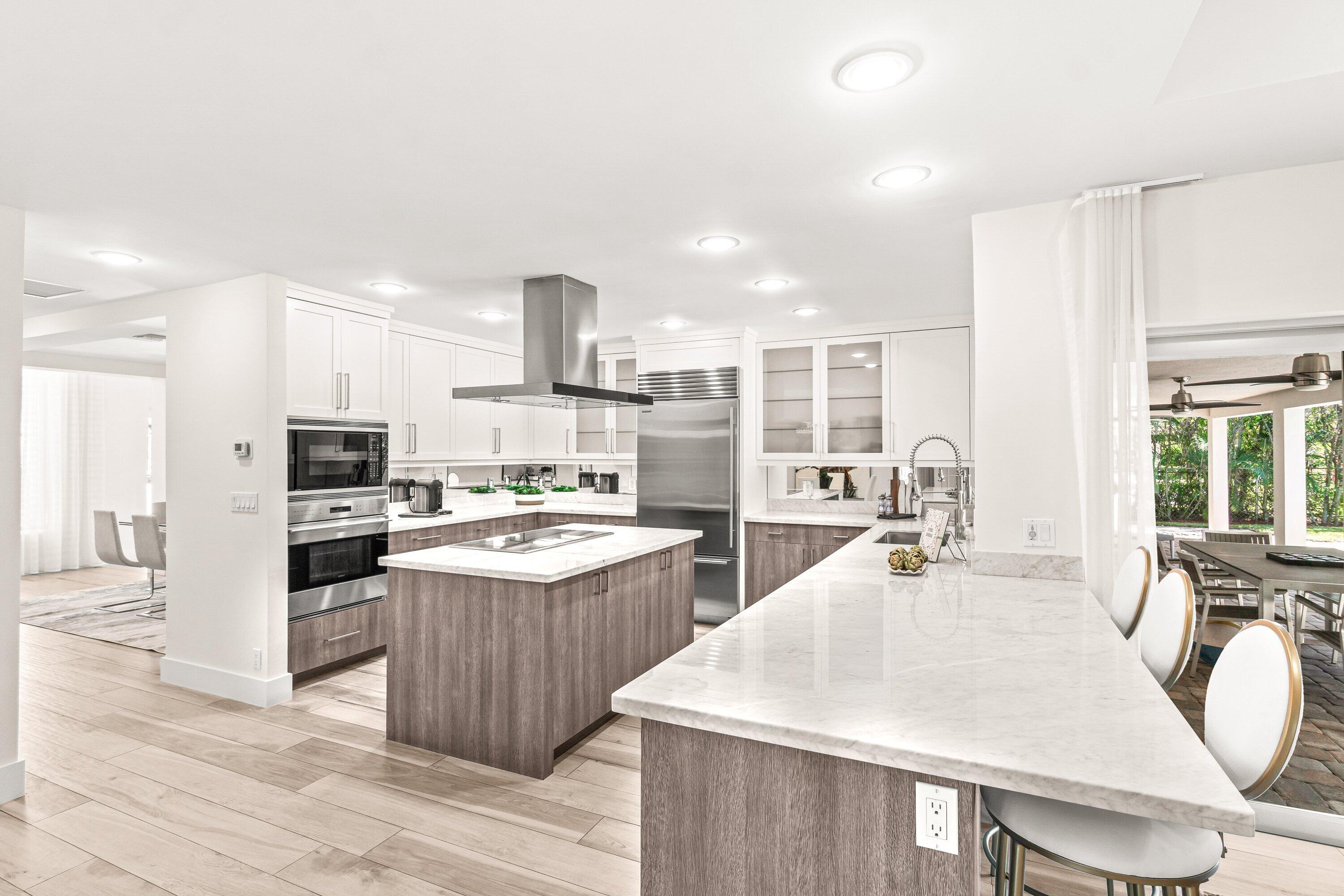 2367 Queen Palm Road Boca Raton, FL 33432 - Photo 10 of 45 a large kitchen with kitchen island a stove a sink a refrigerator and a dining table with wooden floor
