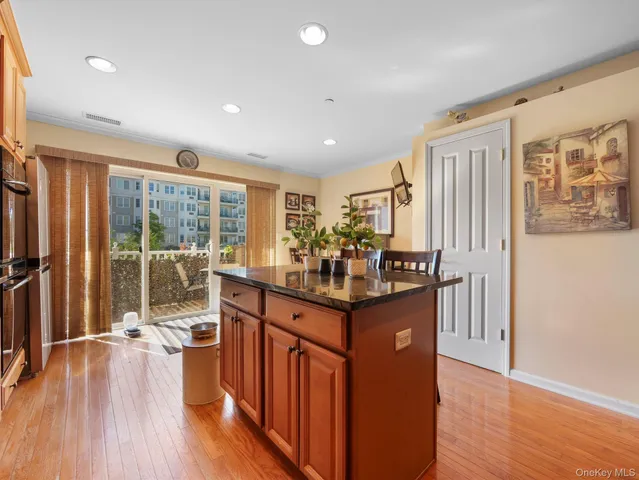 a kitchen with stainless steel appliances granite countertop a refrigerator a sink dishwasher a stove and a dining table with wooden floor