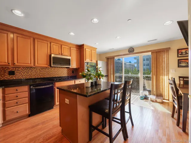 a kitchen with stainless steel appliances granite countertop wooden floor cabinets dining table and chairs