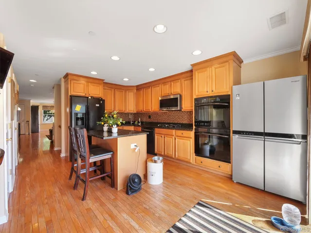 a kitchen with granite countertop a refrigerator a oven a stove and white cabinets with wooden floor