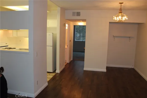 an empty room with wooden floor mirror and windows