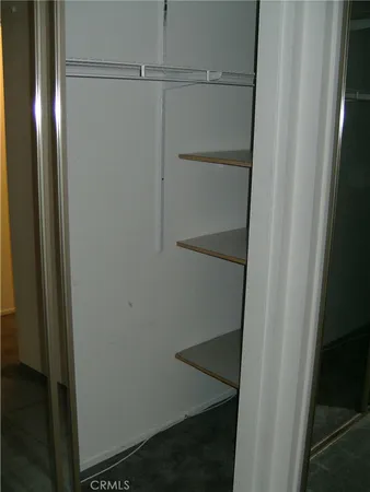 an empty room with closet and a chandelier fan