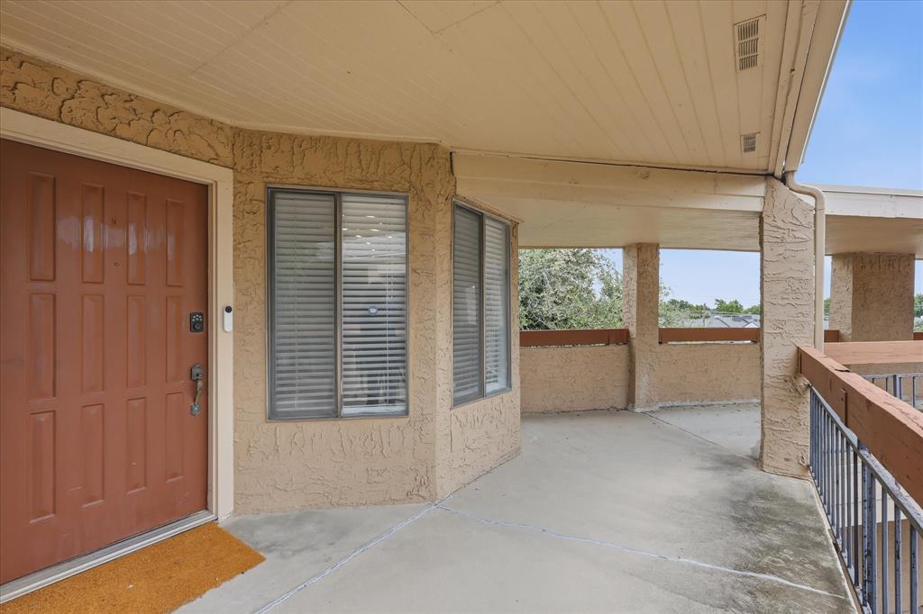 5550 Spring Valley Road, Unit A31 Dallas, TX 75254 - Photo 16 of 24 Covered outdoor patio with textured stucco walls, a paneled entry door, and integrated window blinds