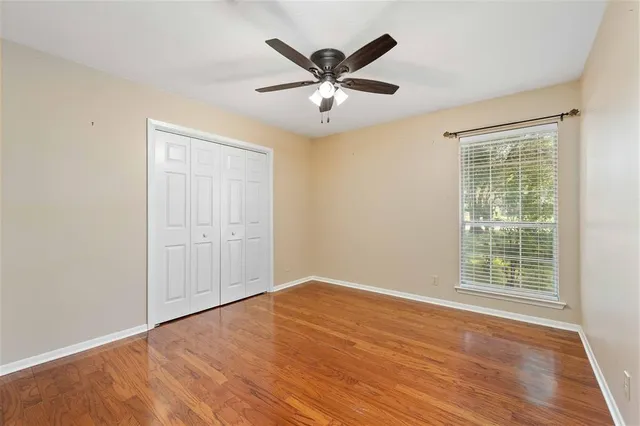 an empty room with wooden floor and ceiling fan