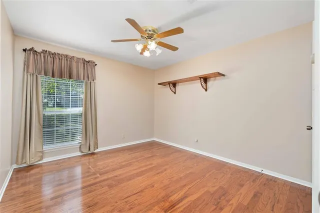 an empty room with wooden floor fan and windows