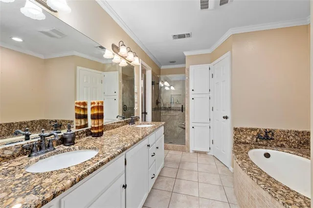 a spacious bathroom with a granite countertop double vanity sink a mirror and a bathtub