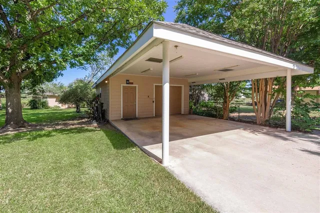 a view of a white house with a small yard plants and large tree